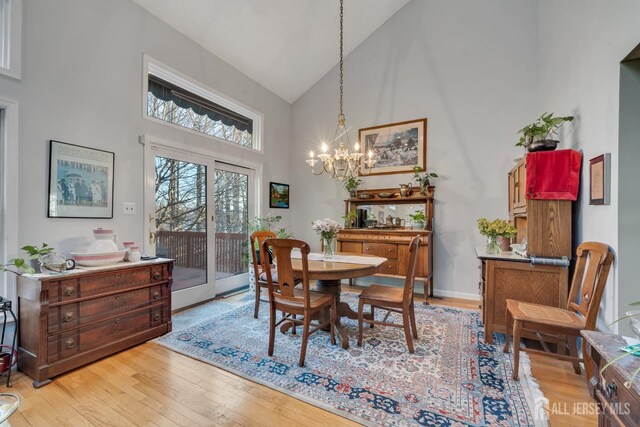 dining room featuring high vaulted ceiling, a notable chandelier, and light hardwood / wood-style flooring