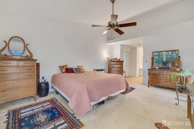 bedroom featuring lofted ceiling, a textured ceiling, ceiling fan, and light colored carpet