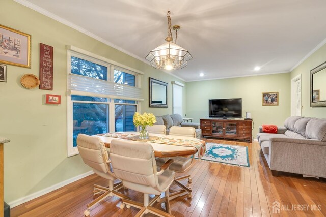 living room featuring ornamental molding, an inviting chandelier, and light hardwood / wood-style floors