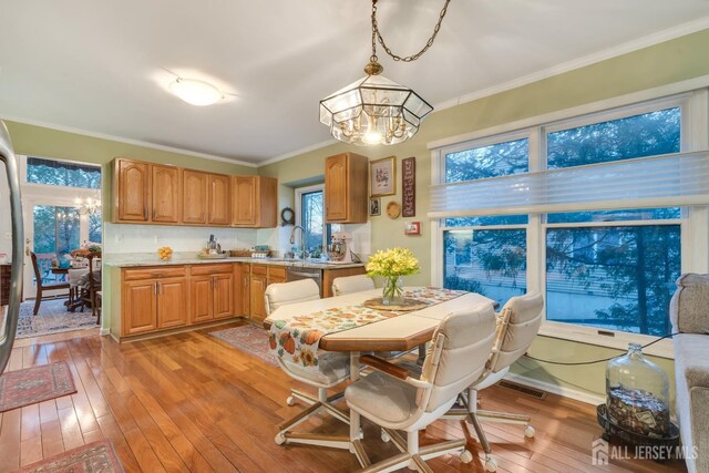 dining room with sink, ornamental molding, and light hardwood / wood-style floors