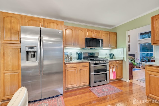 kitchen with ornamental molding, tasteful backsplash, stainless steel appliances, and light hardwood / wood-style flooring