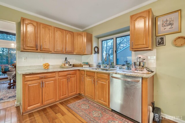 kitchen with light stone countertops, decorative backsplash, sink, light hardwood / wood-style flooring, and stainless steel dishwasher