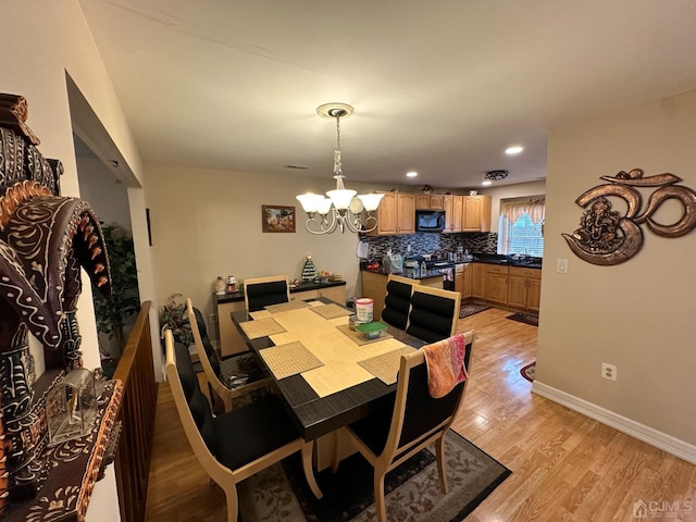 dining area with light hardwood / wood-style floors and an inviting chandelier