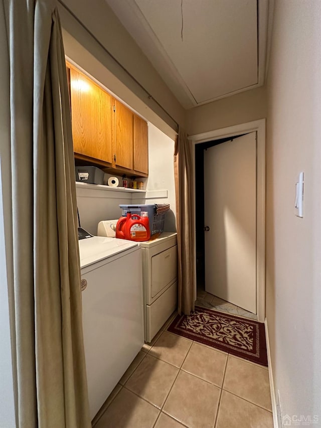 washroom featuring light tile patterned flooring, washer and clothes dryer, and cabinets