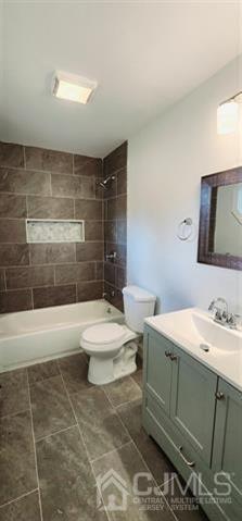 full bathroom with tile patterned flooring, tiled shower / bath, vanity, and toilet