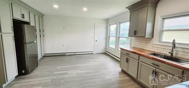 kitchen featuring sink, butcher block counters, plenty of natural light, and stainless steel fridge