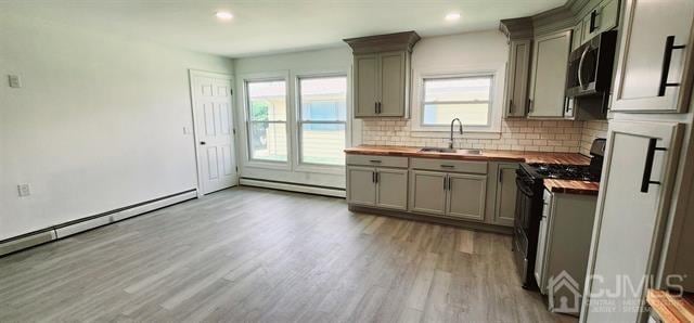 kitchen with appliances with stainless steel finishes, butcher block countertops, and plenty of natural light