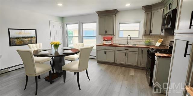 kitchen featuring light wood-type flooring, gray cabinetry, decorative backsplash, black range with gas stovetop, and butcher block countertops