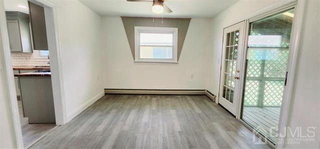 interior space featuring light hardwood / wood-style floors, ceiling fan, and a baseboard heating unit