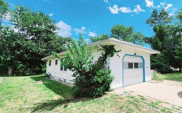 view of side of home featuring a garage, an outdoor structure, and a yard