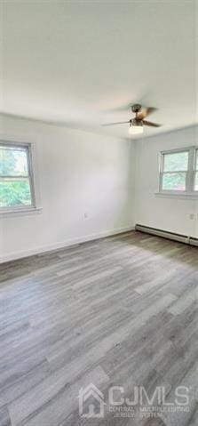 unfurnished room featuring light hardwood / wood-style flooring, ceiling fan, baseboard heating, and plenty of natural light