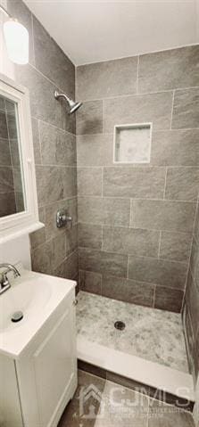 bathroom featuring a tile shower and vanity