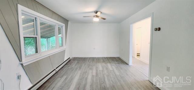 unfurnished room featuring a baseboard heating unit, ceiling fan, and light hardwood / wood-style flooring