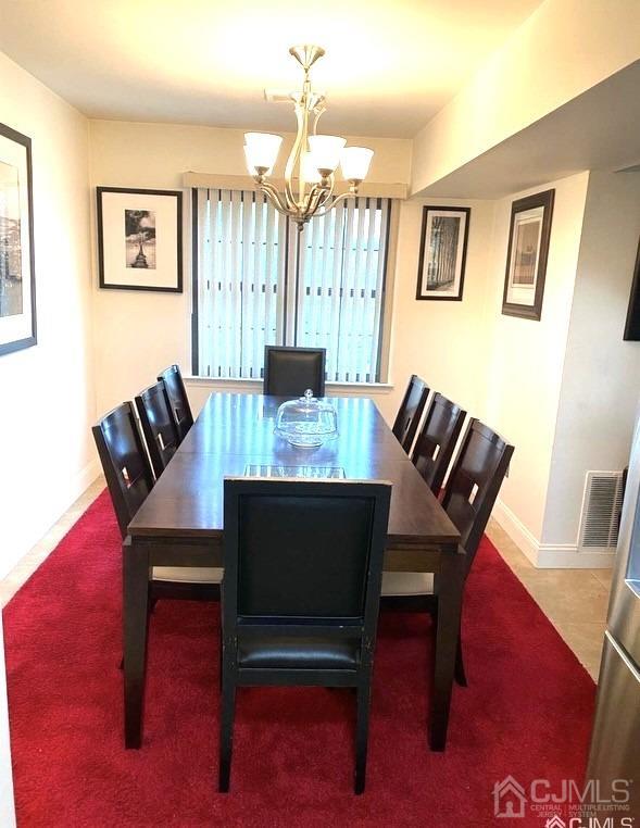 dining area with tile patterned floors and an inviting chandelier