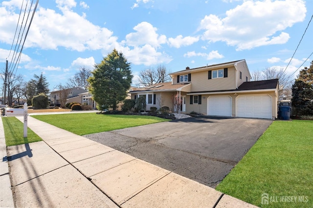 traditional home with a front yard, an attached garage, and aphalt driveway