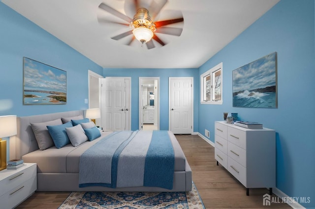 bedroom featuring connected bathroom, baseboards, a ceiling fan, and dark wood-style flooring