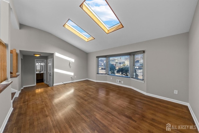 unfurnished living room featuring visible vents, vaulted ceiling with skylight, baseboards, and wood finished floors