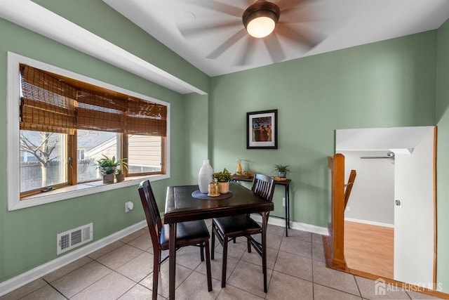 tiled dining room featuring baseboards, visible vents, and ceiling fan