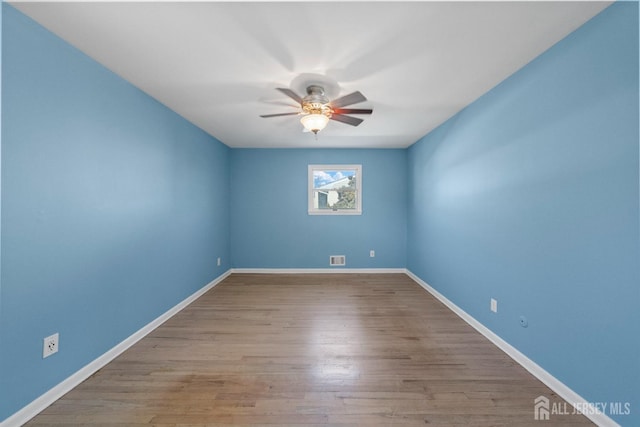 spare room featuring visible vents, wood finished floors, baseboards, and ceiling fan