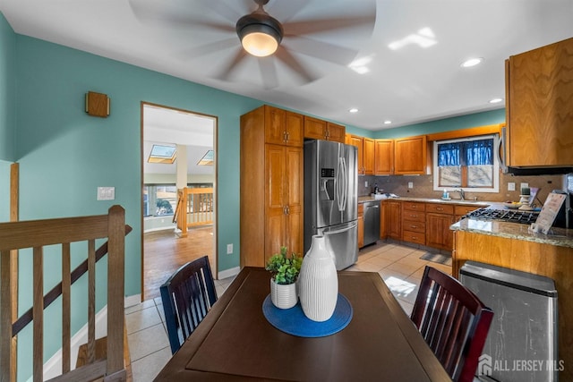 kitchen featuring a sink, stainless steel appliances, brown cabinets, and light tile patterned flooring