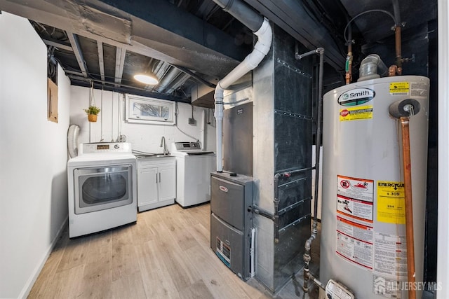 washroom featuring baseboards, light wood finished floors, cabinet space, gas water heater, and washer and clothes dryer