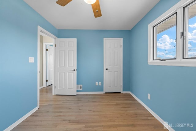 unfurnished bedroom featuring visible vents, baseboards, light wood-style floors, and ceiling fan