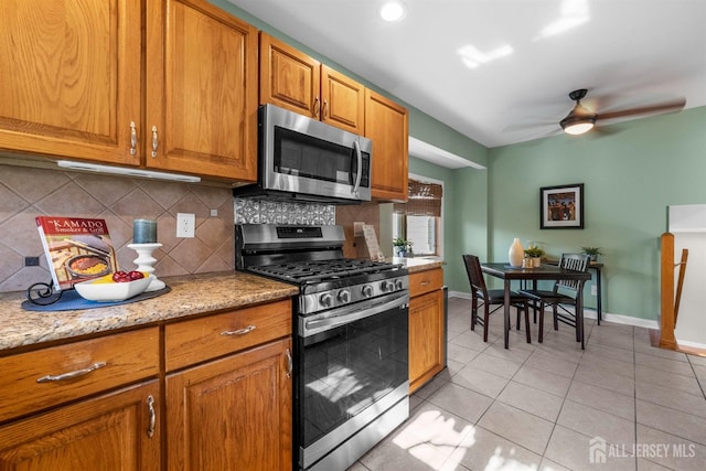 kitchen featuring light tile patterned flooring, brown cabinets, backsplash, and stainless steel appliances