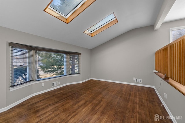 spare room with lofted ceiling with skylight, wood finished floors, baseboards, and visible vents