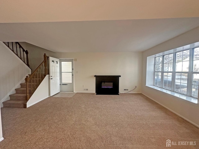 unfurnished living room with stairway, baseboards, and carpet floors