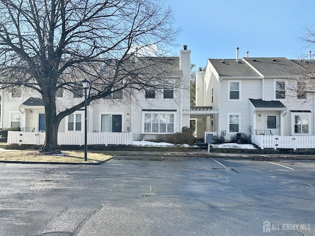 view of front of home featuring uncovered parking, a chimney, and fence