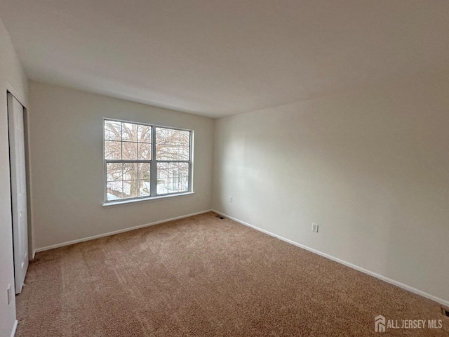 unfurnished bedroom featuring baseboards, carpet, visible vents, and a closet