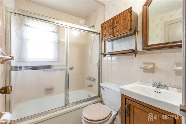 78 Bernard St, Carteret, NJ 07008 - bathroom with shower / bath combination with glass door, vanity, wallpapered walls, tile walls, and backsplash