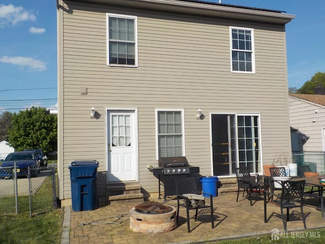 back of property featuring entry steps, fence, a patio area, and an outdoor fire pit