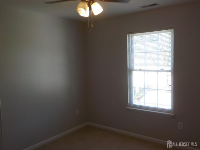 carpeted spare room with a ceiling fan and baseboards