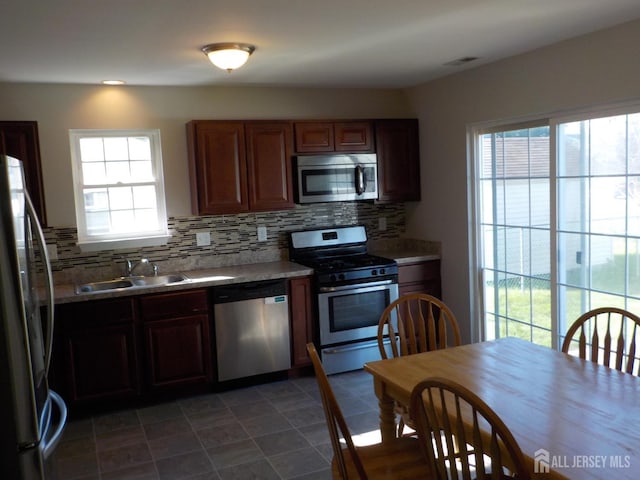 kitchen with stainless steel appliances, a sink, decorative backsplash, and light countertops