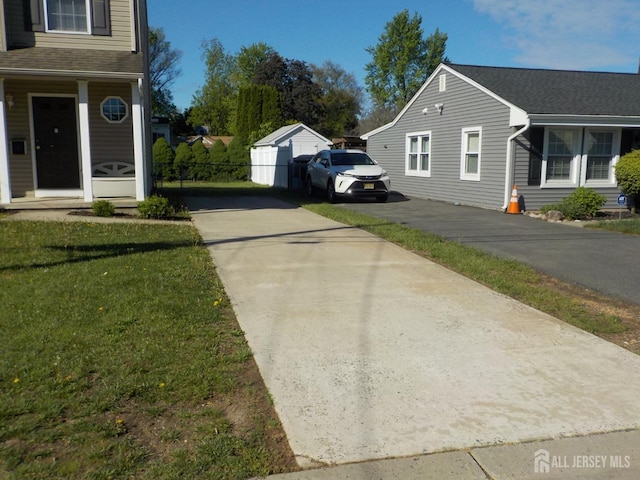 view of side of home featuring driveway, a yard, and roof with shingles