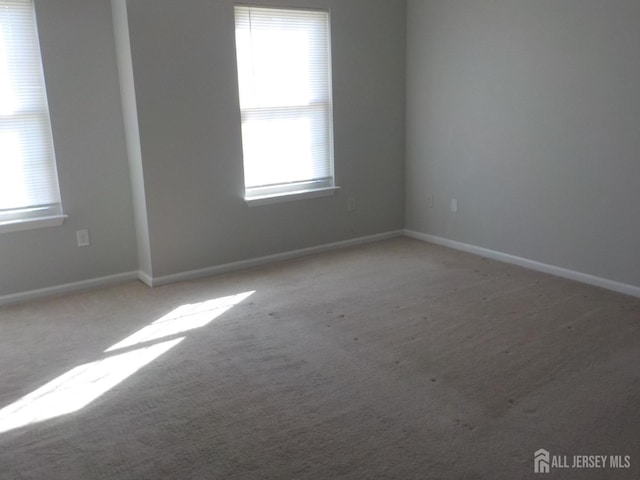 carpeted spare room featuring baseboards