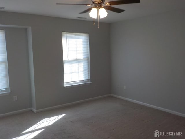 carpeted spare room with ceiling fan and baseboards
