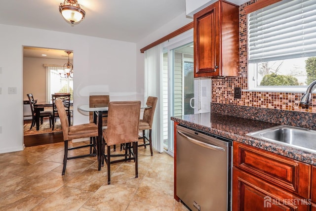 kitchen featuring decorative backsplash, a sink, a chandelier, dishwasher, and baseboards