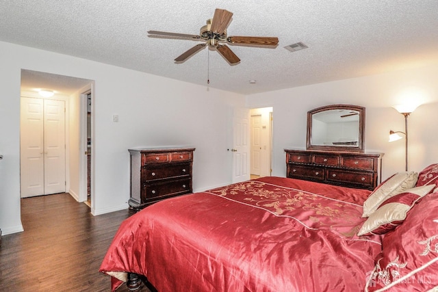 bedroom featuring dark wood-style floors, a textured ceiling, visible vents, and baseboards