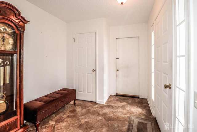 hallway with a textured ceiling and baseboards