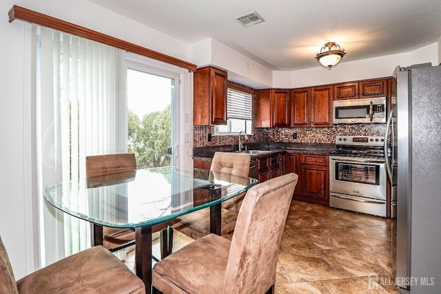 kitchen with stainless steel appliances, visible vents, a sink, and backsplash