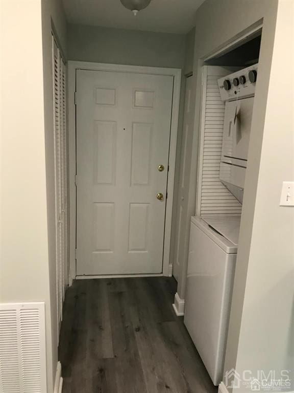 washroom with dark wood-style flooring, laundry area, visible vents, and stacked washing maching and dryer