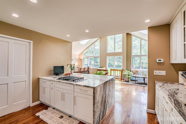 9 NW Fielding Pl, Edison, NJ 08820 - kitchen with a peninsula, a skylight, dark wood finished floors, light stone counters, and stainless steel gas cooktop