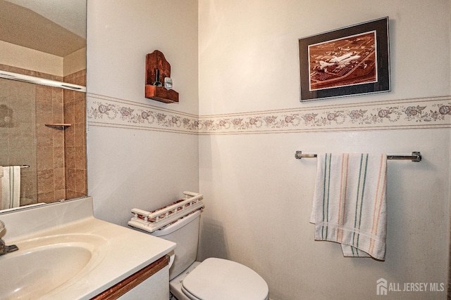 bathroom with a shower with door, vanity, and toilet