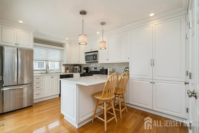 580 Patten Ave Unit 53, Long Branch, NJ 07740 - kitchen featuring stainless steel appliances, white cabinets, a kitchen bar, light countertops, and light wood-style flooring