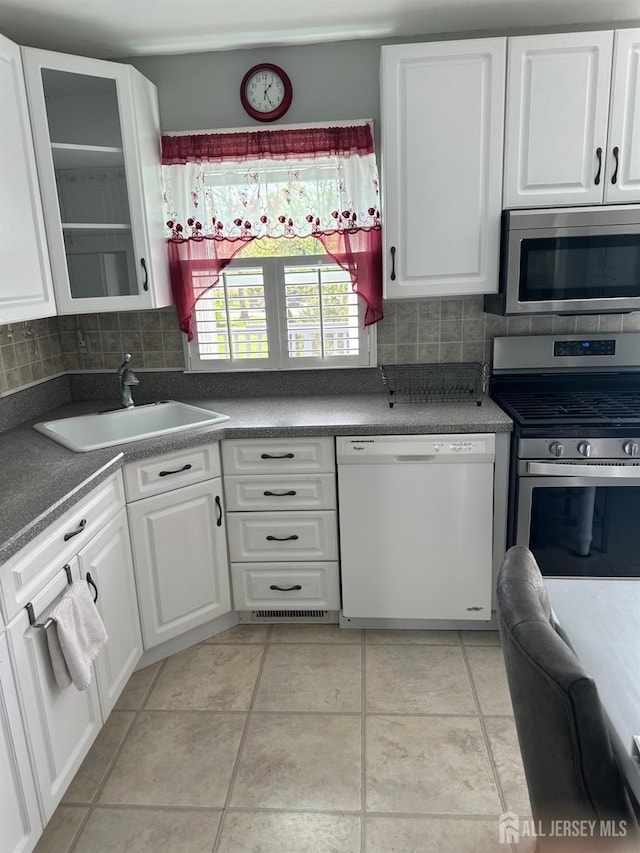 68 Suydam Ave, Edison, NJ 08817 - kitchen featuring appliances with stainless steel finishes, tasteful backsplash, white cabinets, dark countertops, and glass insert cabinets