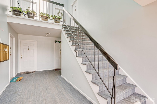 stairs featuring baseboards, a towering ceiling, and carpet floors