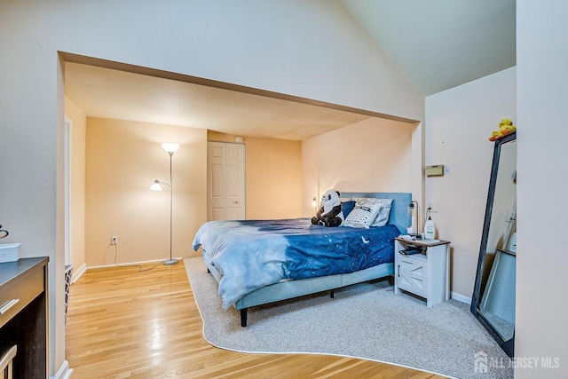 bedroom featuring light wood finished floors and vaulted ceiling