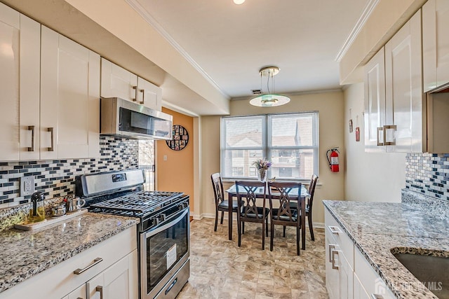 kitchen with light stone countertops, ornamental molding, appliances with stainless steel finishes, white cabinetry, and tasteful backsplash